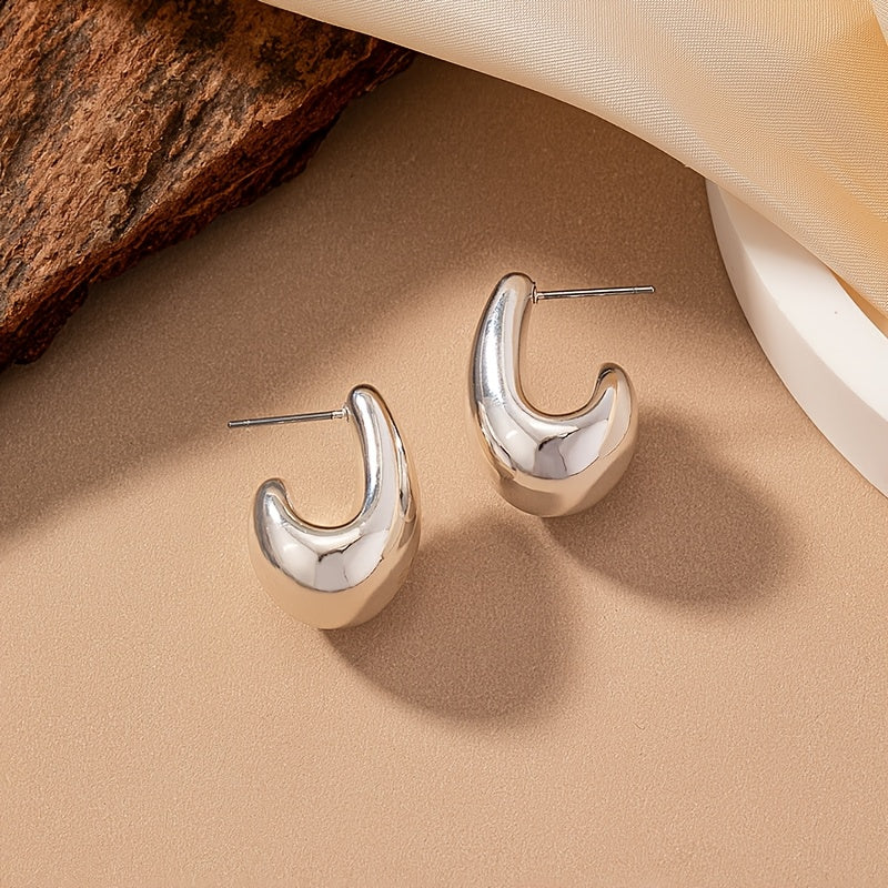 Minimalistische goldene Ohrstecker in skulpturaler C-Form